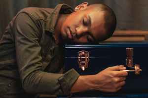 man in green jacket leaning head on blue case